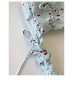 Détail du tissu à pois bleu clair avec nœuds rouges et fermeture par cordon