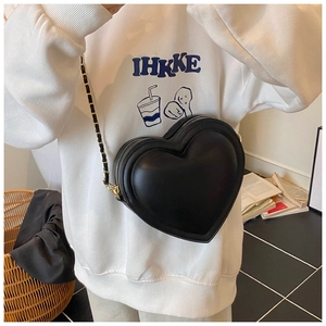 Détail d'un sac à bandoulière en cuir noir en forme de cœur avec chaîne sur un mannequin