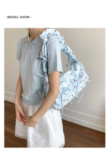 Détail du sac à bandoulière bleu clair à nœuds rouges avec bandoulière à volants