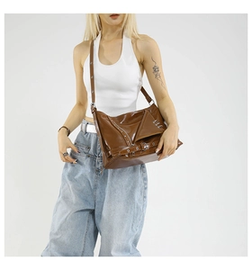 Dettaglio macro della borsa tote marrone lucida stile moto con fibbie in metallo argento