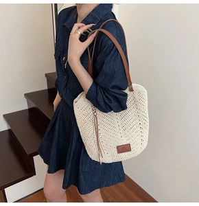 Detail of woven tote bag featuring beige V-pattern texture and brown leather strap
