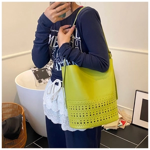 Detail einer lindgrünen Beuteltasche mit runden Lochmustern und Lederstruktur am Model