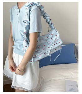 Détail d'un sac à bandoulière bleu clair à fleurs avec sangle à volants et nœuds