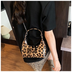 Detail of leopard print handbag featuring glossy patent leather and silver chain strap