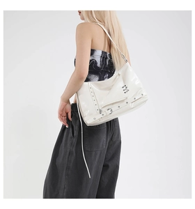 Detail of white glossy patent leather shoulder bag with silver rivets and punk biker style