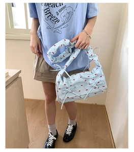 Détail du sac sous le bras plissé bleu clair avec imprimé nœuds rouges et tissu doux