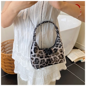 Detailed view of leopard print glossy faux leather bag with silver chain strap on model