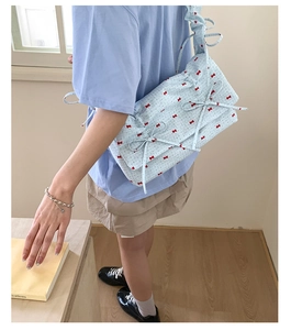 Détail du sac à bandoulière en tissu bleu clair avec motifs de mini nœuds rouges