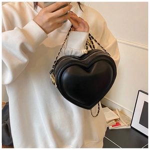 Dettaglio della borsa a tracolla a forma di cuore con catena dorata e texture in pelle nera