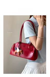Détail d'un sac à bandoulière en cuir rouge brillant avec charm pégase et logo embossé