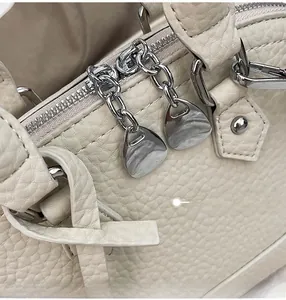 Detail der cremefarbenen Muschel-Tasche mit Kieselleder-Struktur und silbernen Reißverschlüssen