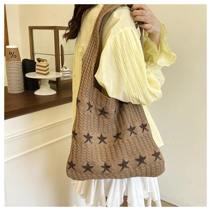 Dettaglio della borsa tote in maglia marrone con stelle indossata su un maglione giallo