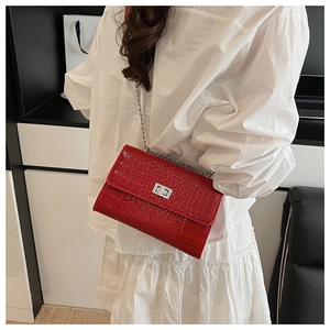 Close-up of stylish red crocodile pattern crossbody bag with silver twist lock on a model