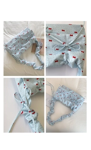 Close-up of blue polka dot crescent bag with ruffled straps and side bow details