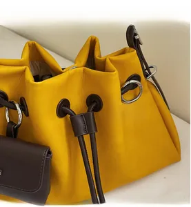 Detailed close-up of yellow leather bucket bag with brown drawstring and hardware accents
