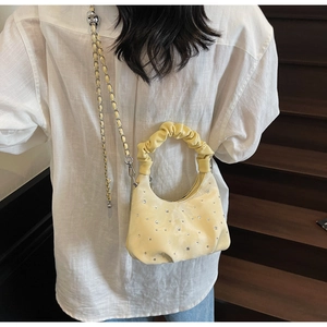 Detail view of yellow pleated crescent bag with sparkling rhinestones and chain strap