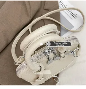 Detailansicht der beigen Lederhandtasche mit herzförmigen Reißverschlüssen und Riemen