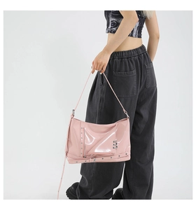 Detail of pink patent leather tote bag with silver zippers, rivets and punk metal rings