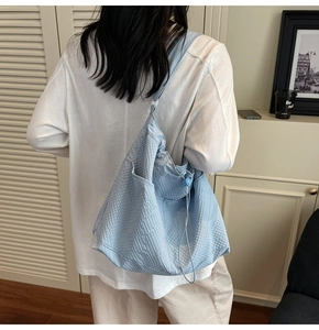 Detailed view of the side pocket and drawstring toggle on the light blue tote bag