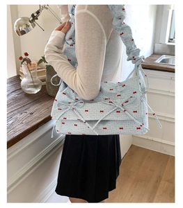 Détail du sac à bandoulière bleu clair avec nœuds décoratifs et bandoulière froncée