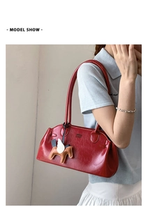 Gros plan sur un sac à bandoulière en cuir verni rouge avec pendentif cheval en cuir