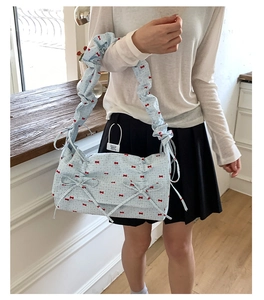 Détail du sac à bandoulière bleu ciel avec bretelles à volants et motifs nœuds rouges