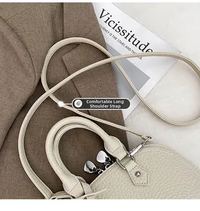 Detail der beigen Lederhandtasche mit silbernem Herz-Reißverschluss und langem Schultergurt