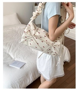 Détail du sac floral avec imprimés nœuds rouges et bandoulière à volants