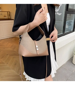 Détail du sac beige avec fermoir tournant argenté et design patchwork en cuir tressé