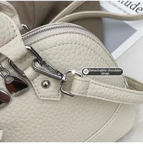 Detail der Lederstruktur mit Lychee-Muster, silberner Metallschnalle und abnehmbarem Gurt