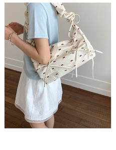 Gros plan d'un sac à bandoulière en tissu avec nœuds rouges et bandoulière froncée