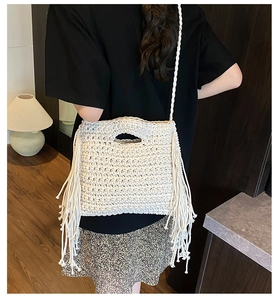 Close-up of a cream woven crossbody bag featuring detailed knit patterns and fringe