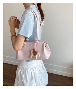 Gros plan d'un sac bowling en cuir rose pâle avec un charm poney surpiqué détaillé