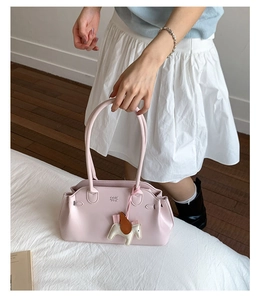 Détail du sac bandoulière rose avec gaufrage COIH NON et charm de cheval en cuir