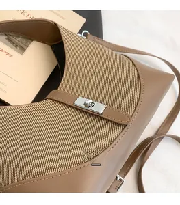 Close-up of contrast leather stitching with woven texture and silver turn-lock buckle