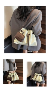 Detail view of cream green bucket bag with brown drawstring and mini charm on shoulder