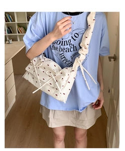 Détail du sac à cordon crème avec imprimé nœud rouge sur toile de coton douce
