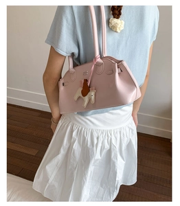 Détails du sac bowling rose en cuir mat avec pendentif cheval et poignées fines