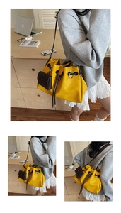 Detail view of a bright yellow bucket bag with brown drawstring and side mini pouch
