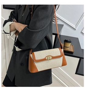 Detail of color-block canvas handbag with gold twist-lock and leather trim accents