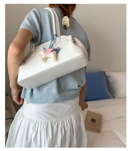 Détail du grand sac à bandoulière blanc avec un charm poney coloré dans un décor de style