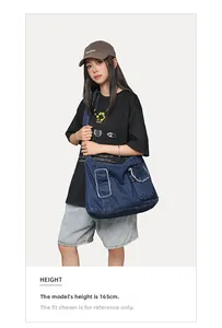 Détail d'un grand sac en jean avec bords effilochés et deux poches à rabat porté par mannequin