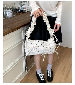 Détail du sac blanc à motifs nœuds rouges avec poignée plissée au style élégant