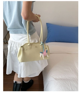 Détail du sac bowling en cuir jaune clair avec logo COIN DN et breloque licorne rose