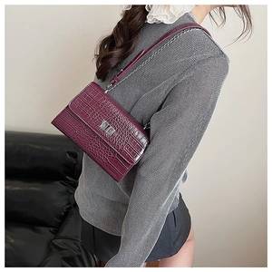 Detail of dark purple crocodile texture bag with silver twist lock and chain strap