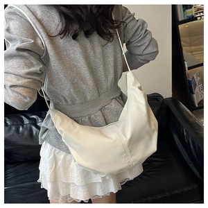 Close-up of ivory crossbody bag with vertical texture worn by model on shoulder