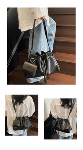 Detail of black leather drawstring bucket bag with mini zip pouch and adjustable strap