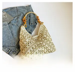 Detail of the woven hollow design and round wooden bead handle on this beige straw tote bag