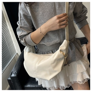 Detail of cream pleated hobo bag with vertical striped texture and wide shoulder strap