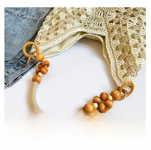 Detail of hand-woven beige tote featuring unique wooden bead handles and crochet texture